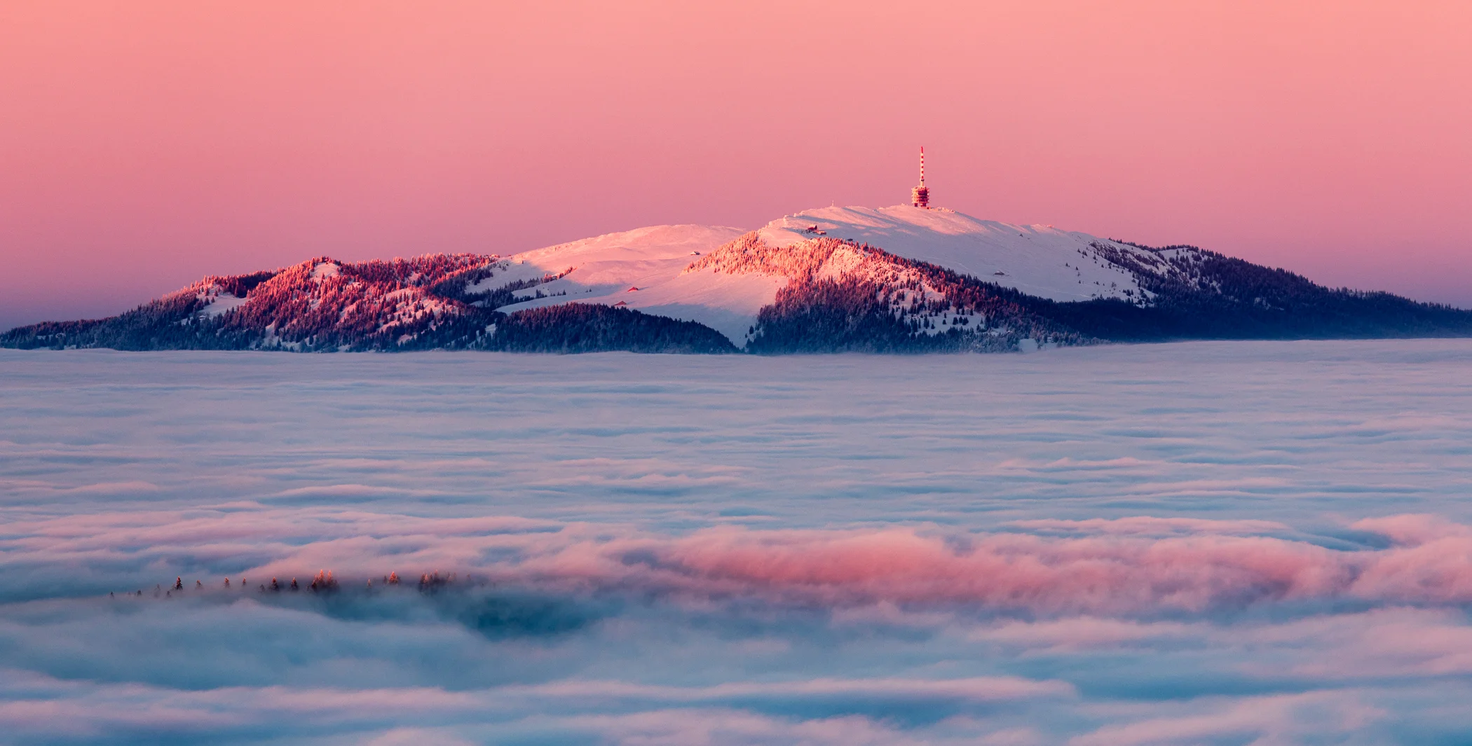 Le Chasseral enneigé émergeant d’une mer de nuages au soleil couchant